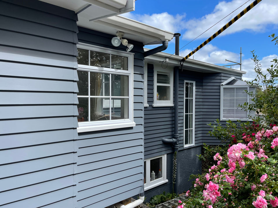 Grey weatherboard home with white trim and flowering garden