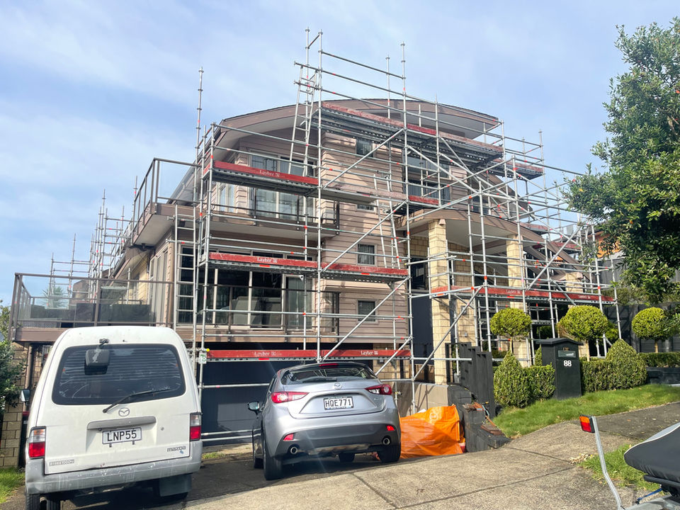 Three-storey building exterior mid-repaint with scaffolding